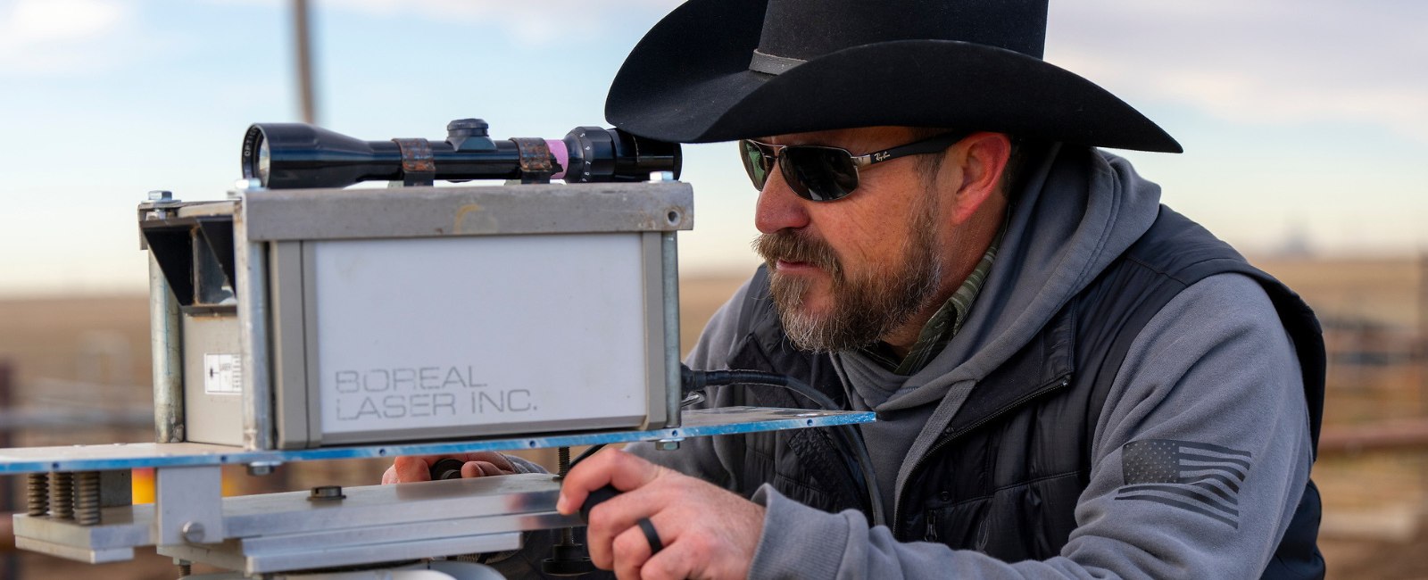 Man looking through scope mounted atop a piece of high-tech equipment on a tri-pod